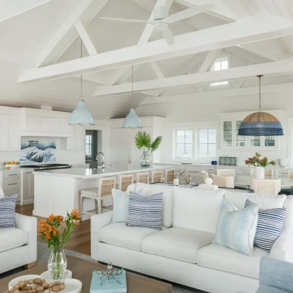 Open-concept living space in a modern beach house featuring white interiors, vaulted ceilings, and coastal decor.