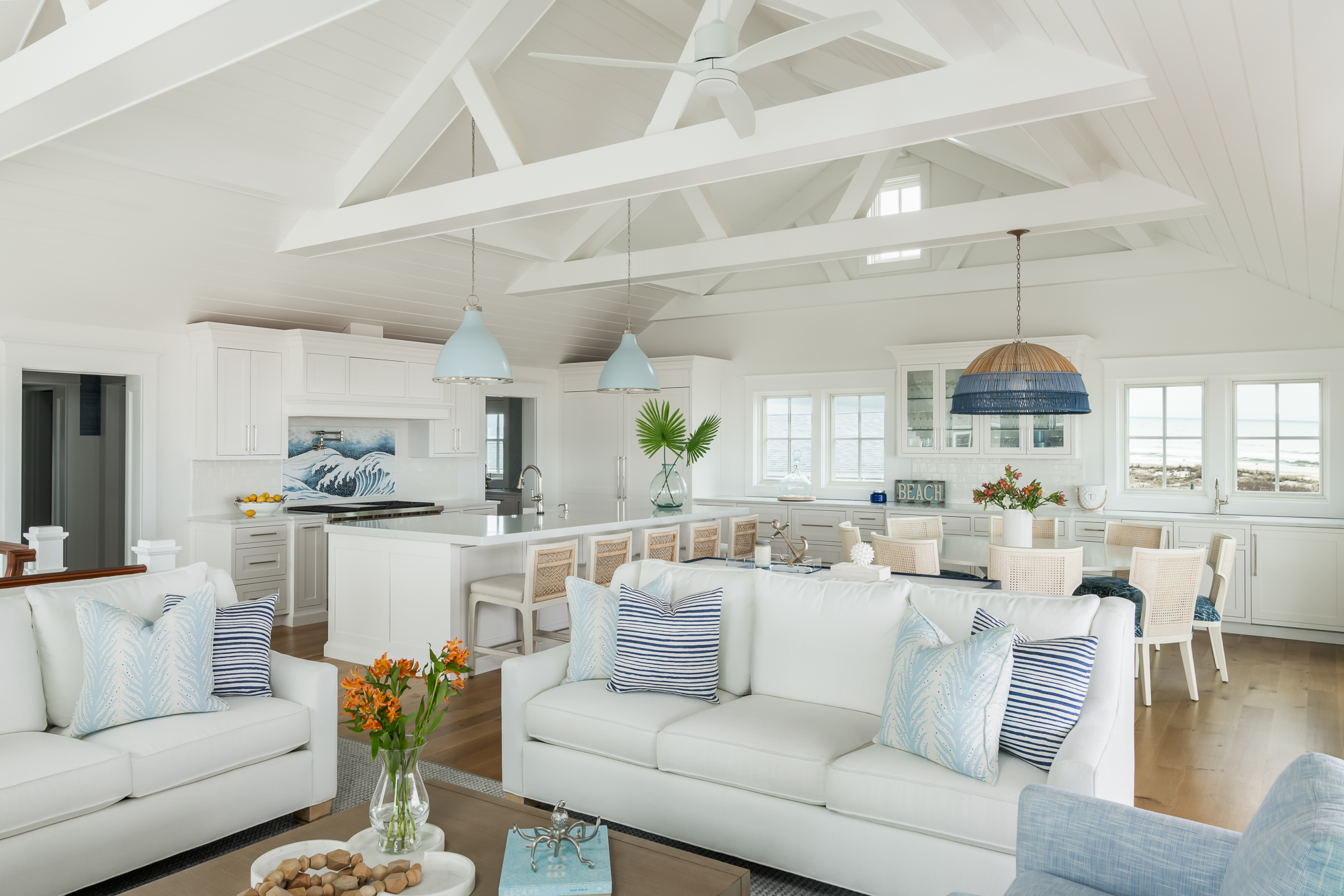 Open-concept living space in a modern beach house featuring white interiors, vaulted ceilings, and coastal decor.