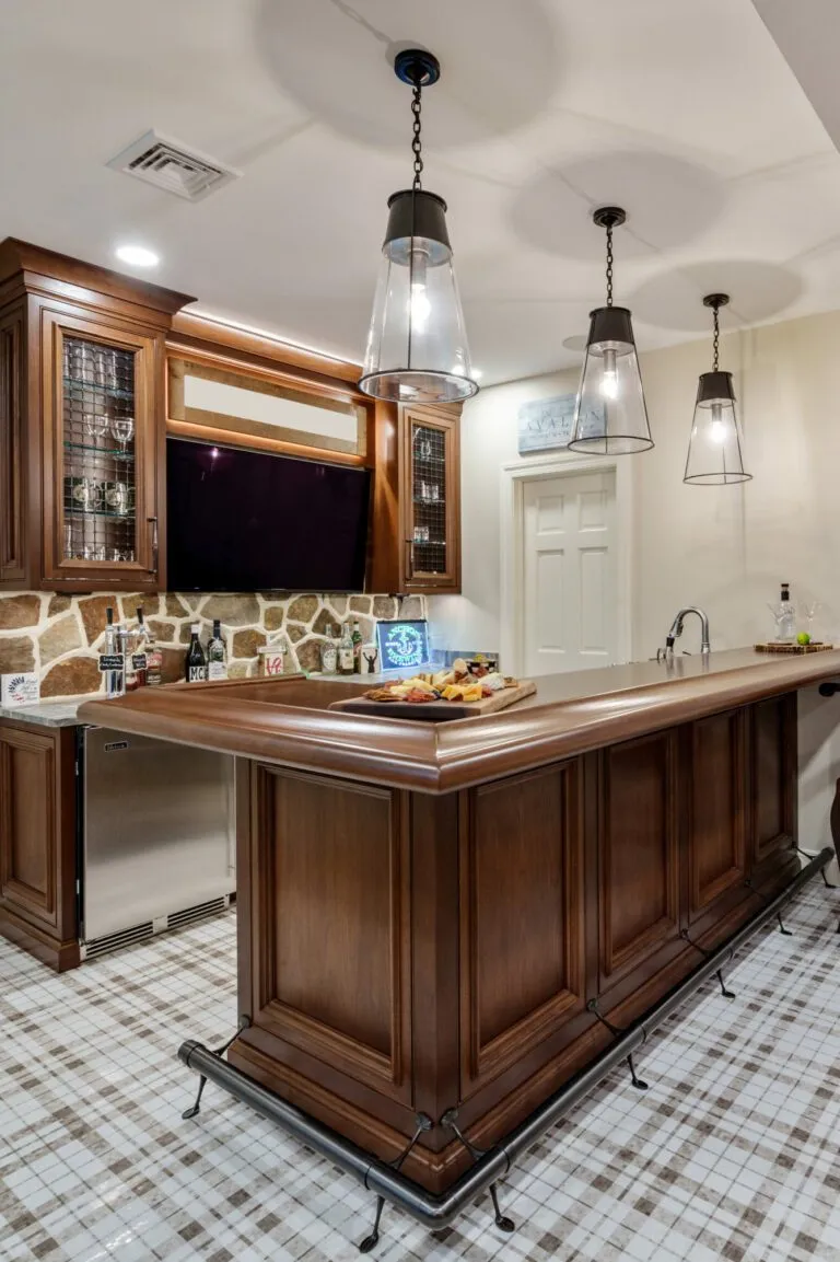 Home bar design in a classic style featuring luxury custom cabinetry in walnut wood with elegant glass accents and pendant lighting, creating a refined entertaining space.