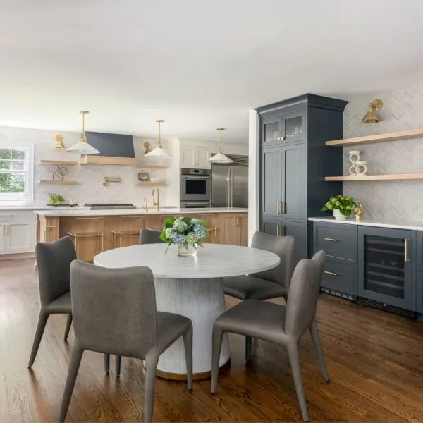 Contemporary kitchen featuring a round marble island, navy cabinets, open shelving, and gold fixtures.