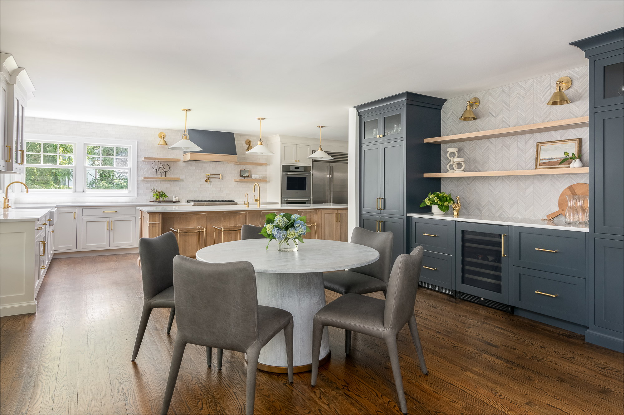 Contemporary kitchen featuring a round marble island, navy cabinets, open shelving, and gold fixtures.