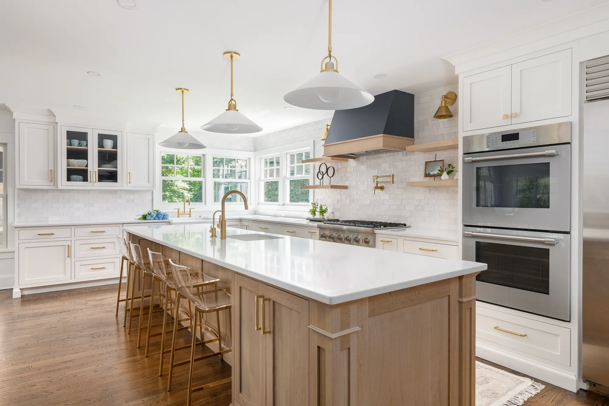 Elegant kitchen featuring a white marble island, gold accents, and white cabinetry with stainless steel appliances.