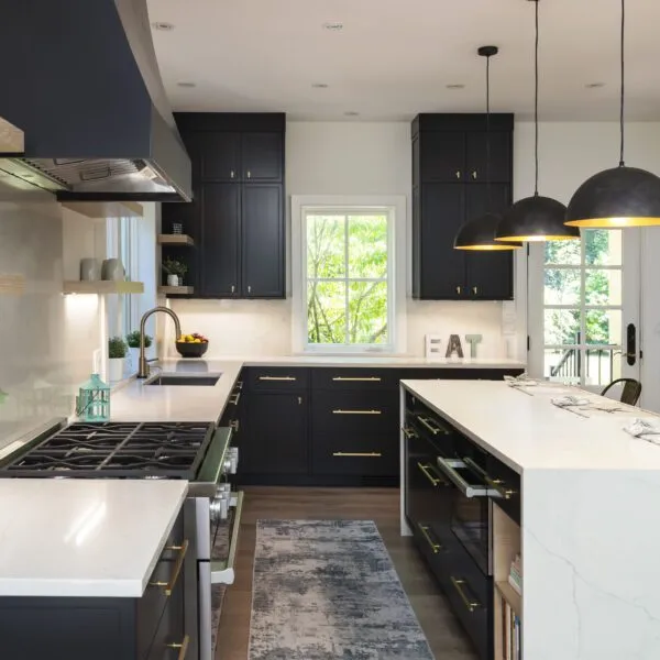 Sleek kitchen with black cabinets, white countertops, a central island, stainless steel appliances, and pendant lights.