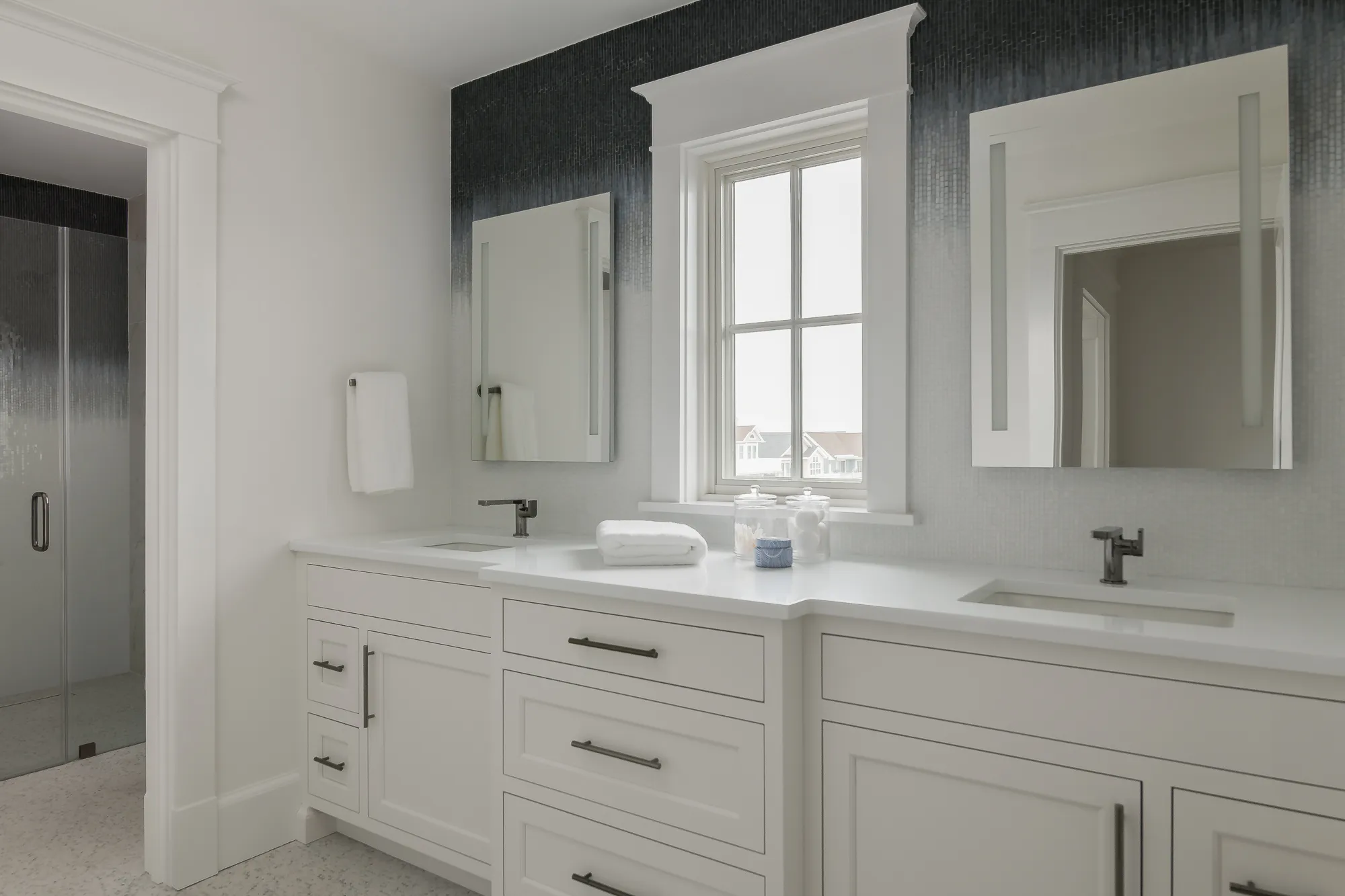 Modern white bathroom vanity with double sinks, large mirrors, and a window providing natural light.