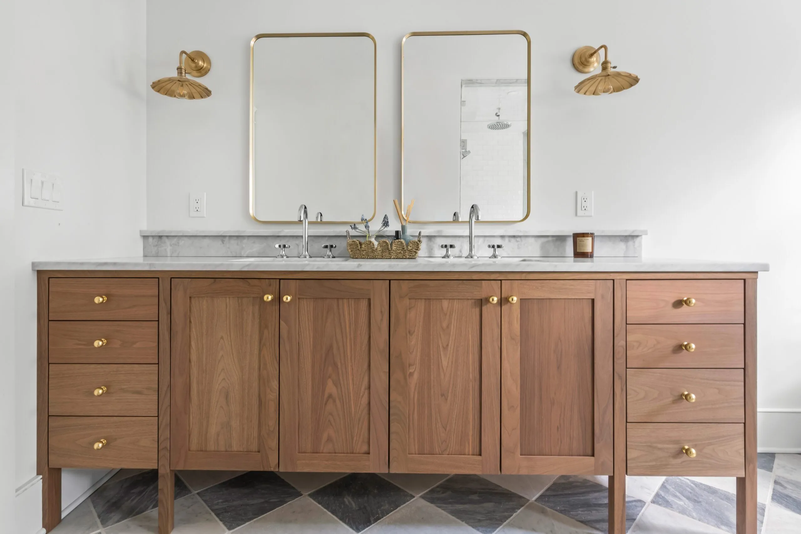 Modern bathroom featuring a wooden double vanity with marble countertop, gold fixtures, and rectangular mirrors.