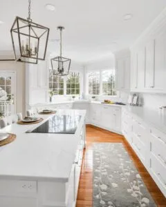 Bright white kitchen with large windows and custom cabinetry designed by Amos E.