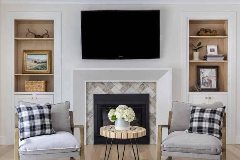 Cozy living room featuring custom cabinets with wooden shelves flanking a modern television and fireplace, adorned with art pieces, books, and decorative items.