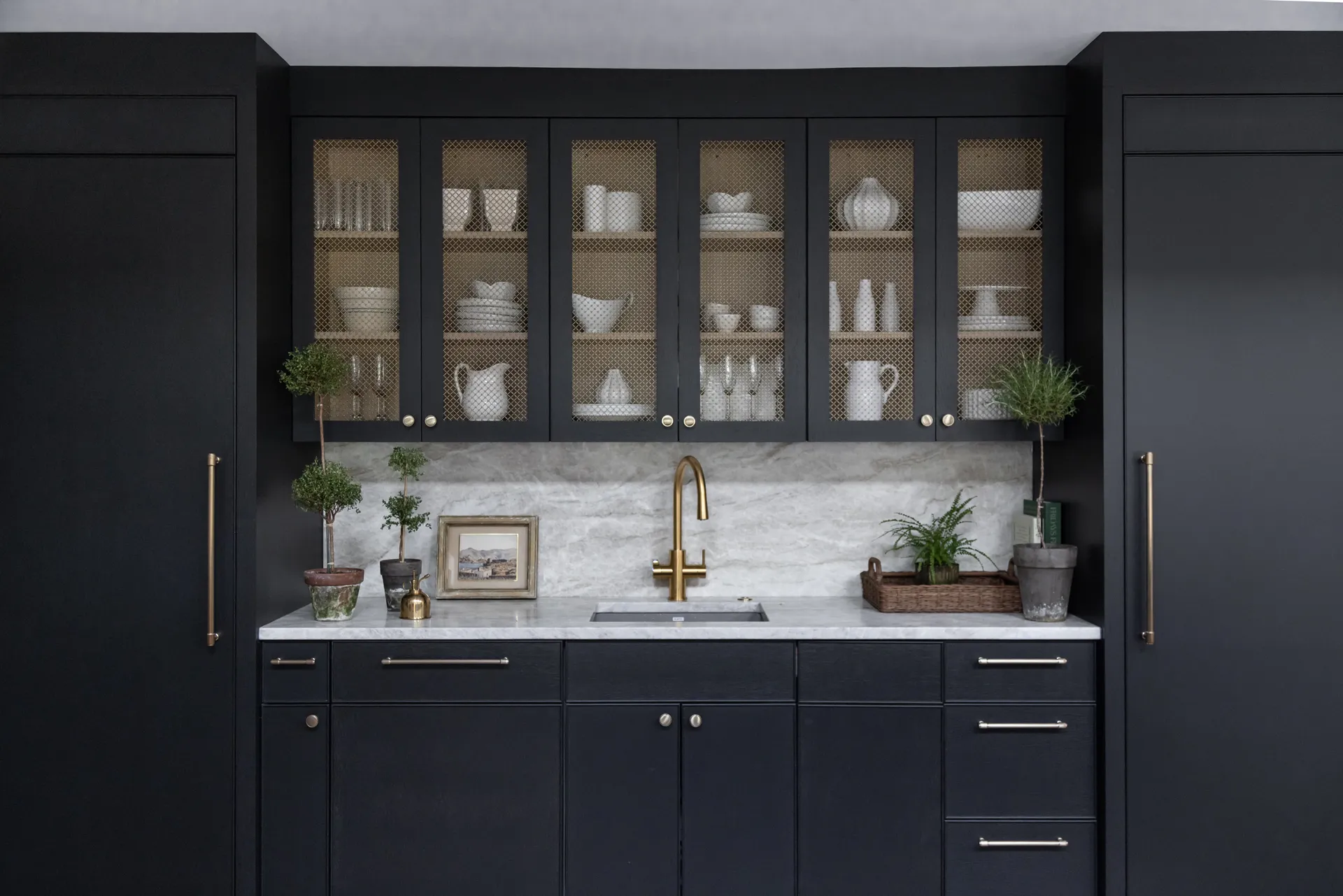 Luxury custom cabinets in a home bar with dark finishes, glass doors, and brass accents.