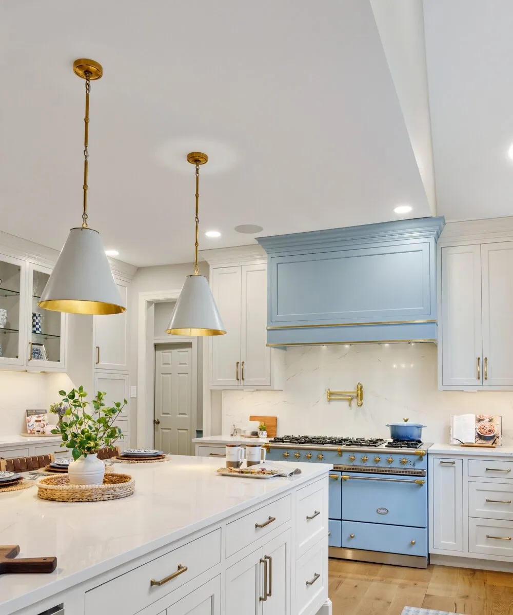 Bright kitchen featuring custom white cabinets, a blue range hood, and gold hardware