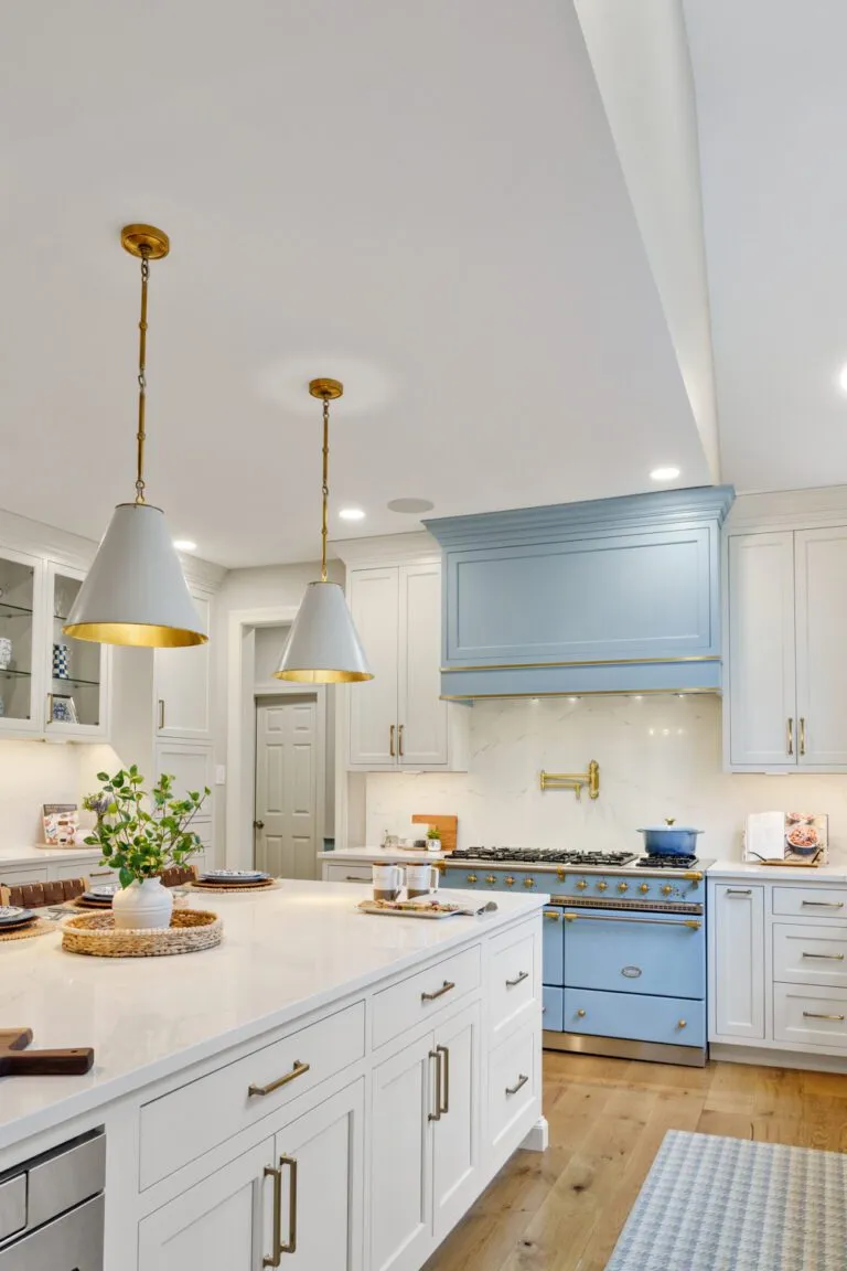 Bright kitchen featuring custom white cabinets, a blue range hood, and gold hardware