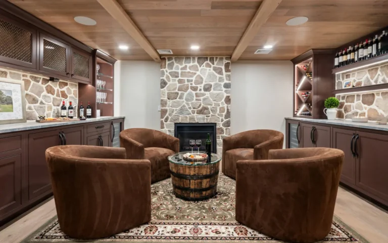 Cozy wine tasting room featuring custom cabinets, stone fireplace, and plush brown chairs.