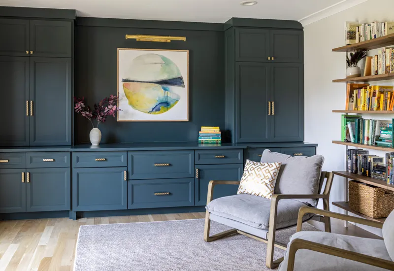 Sophisticated quiet luxury built-in blue cabinetry with gold hardware, integrated shelving, and a comfortable seating area