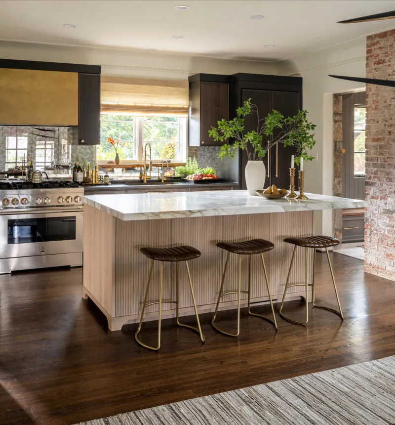 Stunning quiet luxury kitchen featuring a large fluted island, dark wood cabinetry, and an exposed brick accent wall
