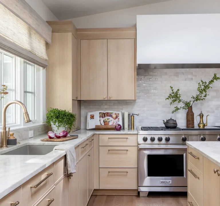 Bright kitchen with white oak cabinets, marble island, stainless steel appliances, and a colorful Persian rug.