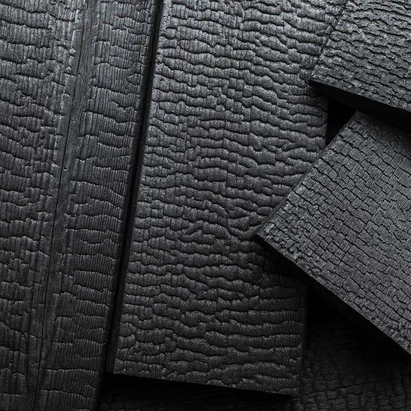 A close-up detail shot of charred wood planks, showcasing the deep black, cracked texture of the Japanese Shou Sugi Ban (Yakisugi) technique.