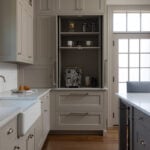A before-and-after view of a custom greige kitchen appliance garage; closed, it looks like a seamless pantry, and open, it reveals a luxury coffee station with an espresso machine.